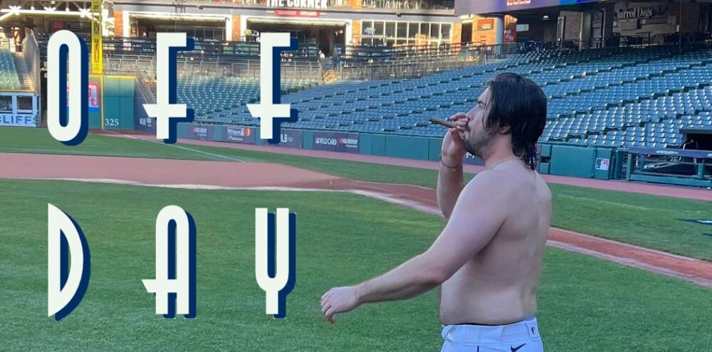 Shirtless man on a baseball field smoking a cigar, with large white and blue text overlays across the left side reading '0+ F DAY'.